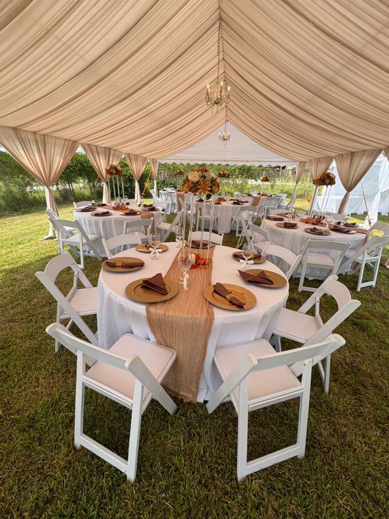 Round event tables finished with linens inside a decorated tent